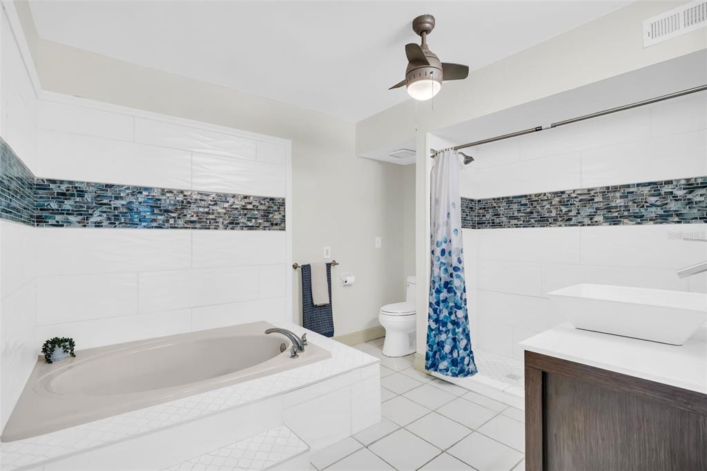 An open-concept living and dining area features wood-look flooring, ceiling fans, and a kitchen pass-through — 1182 NORWOOD AVENUE, CLEARWATER, FL