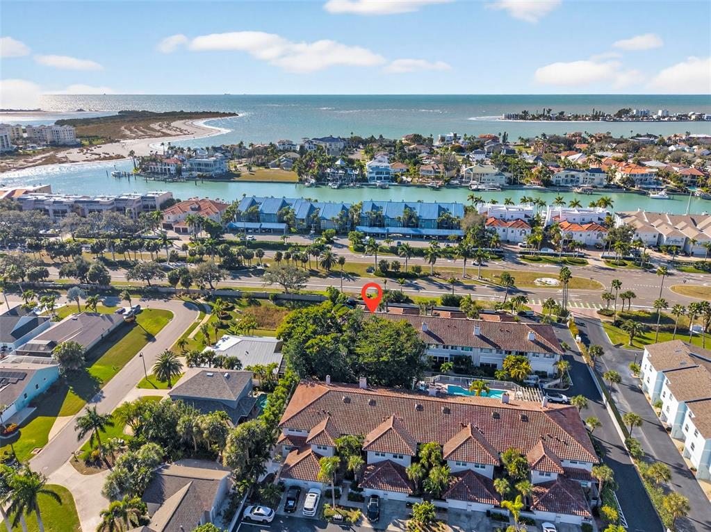 The exterior of a two-story residential building features a paved walkway, palm trees, and garages — 903 PINELLAS BAYWAY S UNIT 308, TIERRA VERDE, FL