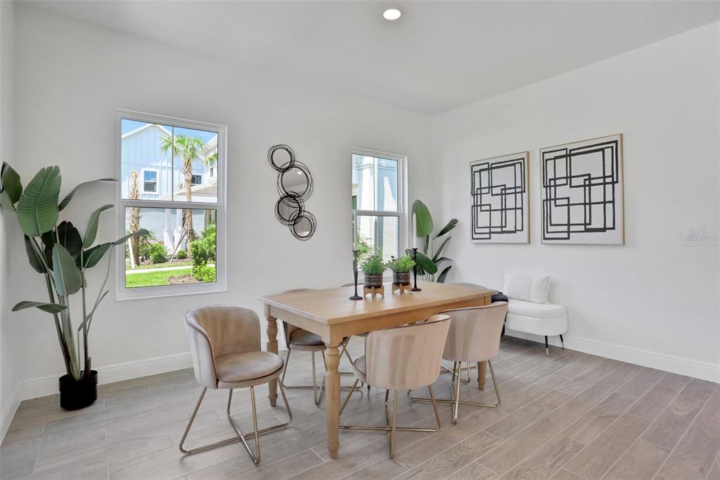 A dining room features a wooden table, four upholstered chairs, two windows, and wall art — 9124 WALCOTT LANE, LAKEWOOD RANCH, FL