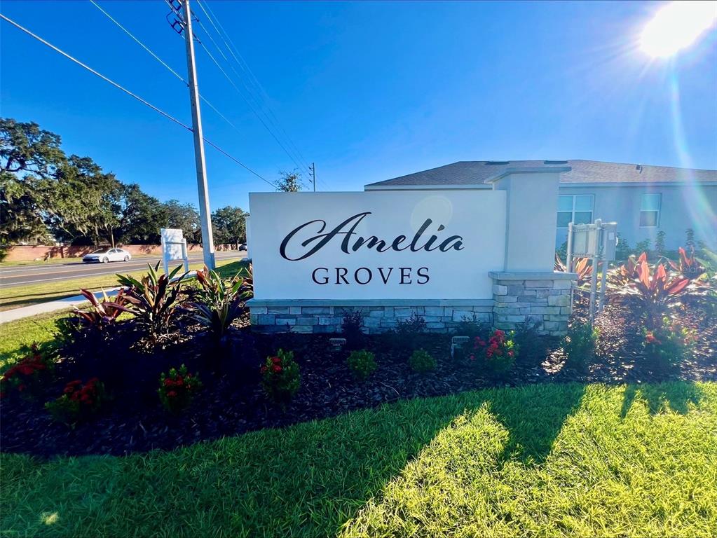 A white monument sign for Amelia Groves stands in a landscaped yard near a road — 6098 WINDY LEAF ALY, ST CLOUD, FL