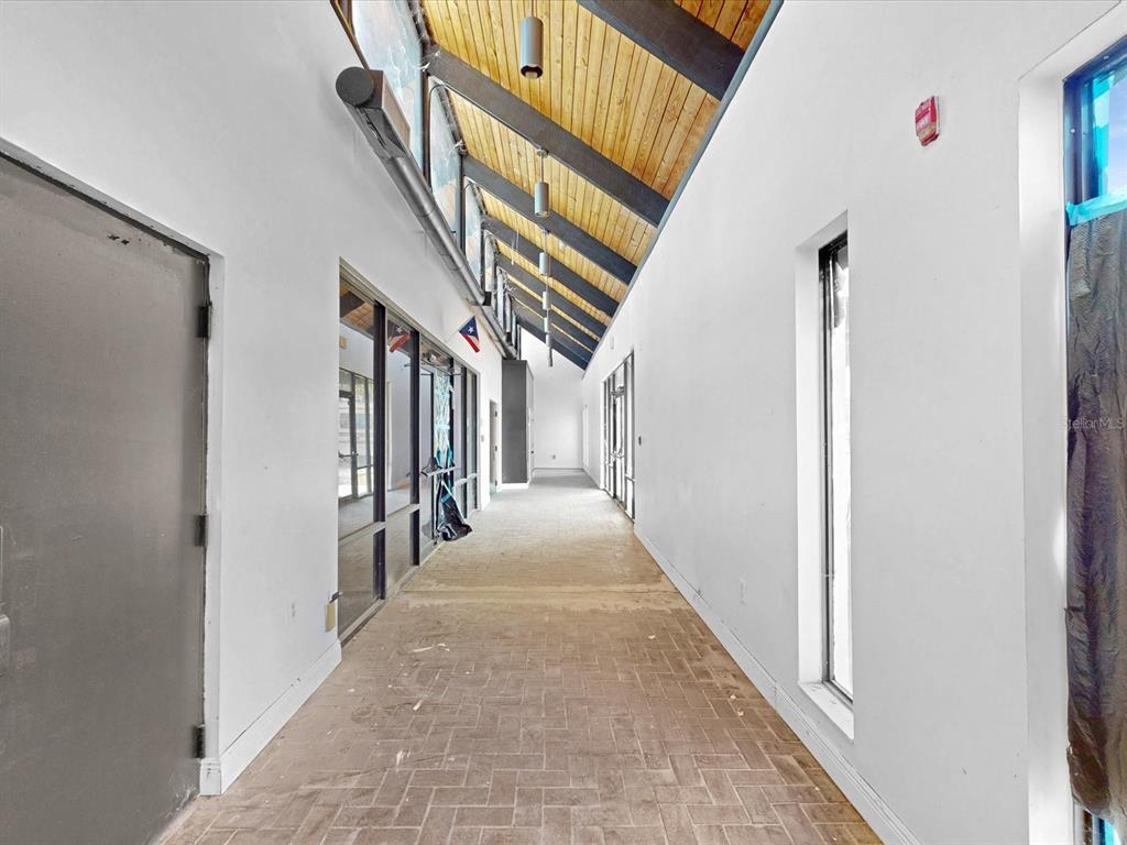 A long hallway features a vaulted wood-paneled ceiling, brick flooring, and glass-paneled doors — 3425 FORSYTH ROAD, WINTER PARK, FL