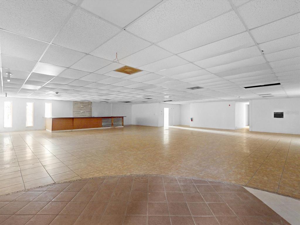 A large, open commercial space features a drop ceiling, tiled flooring, and a wooden bar — 3425 FORSYTH ROAD, WINTER PARK, FL