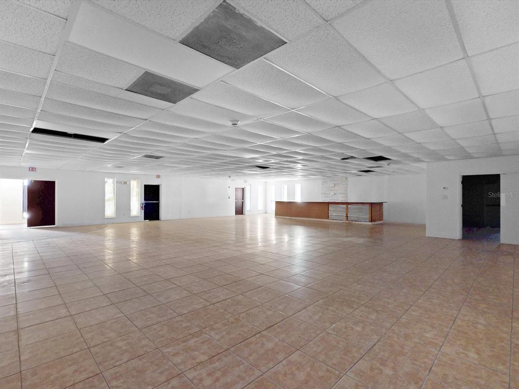 A large, open commercial space features a drop ceiling, tiled floors, and a wooden counter — 3425 FORSYTH ROAD, WINTER PARK, FL