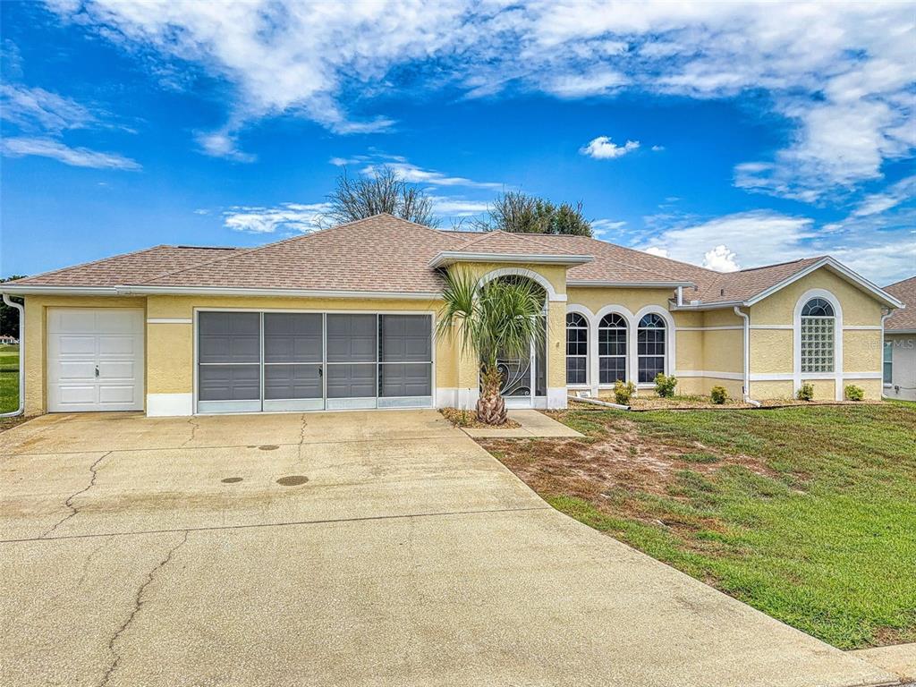 A yellow single-story house with a concrete driveway, a screened garage, and a tiled roof — 2089 NW 50TH CIRCLE, OCALA, FL