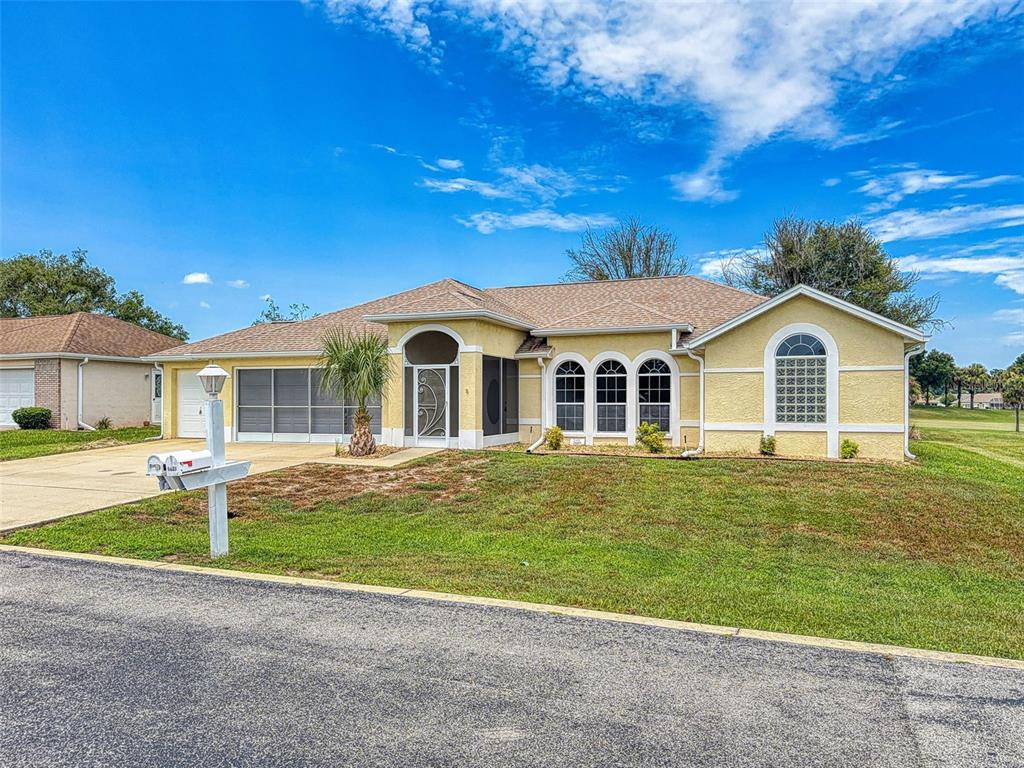 A single-story yellow house with a screened-in entryway, arched windows, and a paved driveway — 2089 NW 50TH CIRCLE, OCALA, FL
