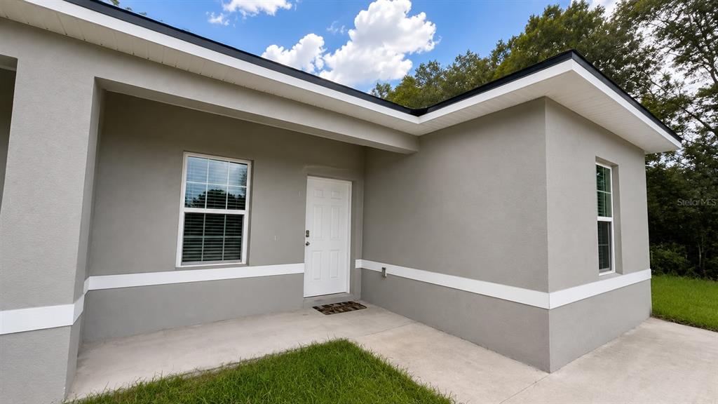 The exterior of a gray house features a white front door, windows, and a concrete porch — 13664 SW 61ST CIRCLE UNIT #2, OCALA, FL