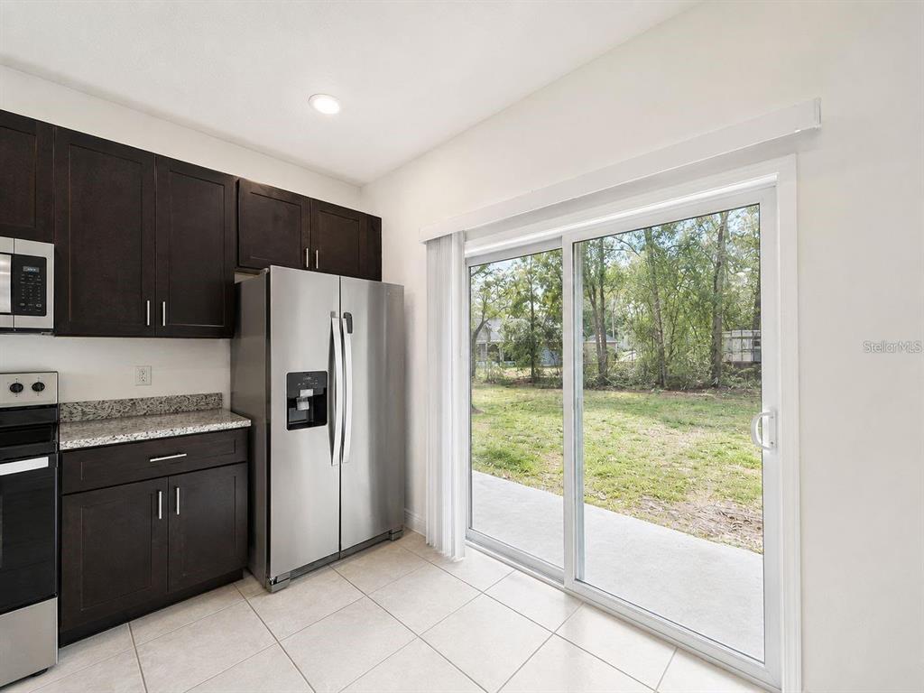 A kitchen with dark cabinets, stainless steel appliances, and a sliding glass door to a yard — 13664 SW 61ST CIRCLE UNIT #2, OCALA, FL