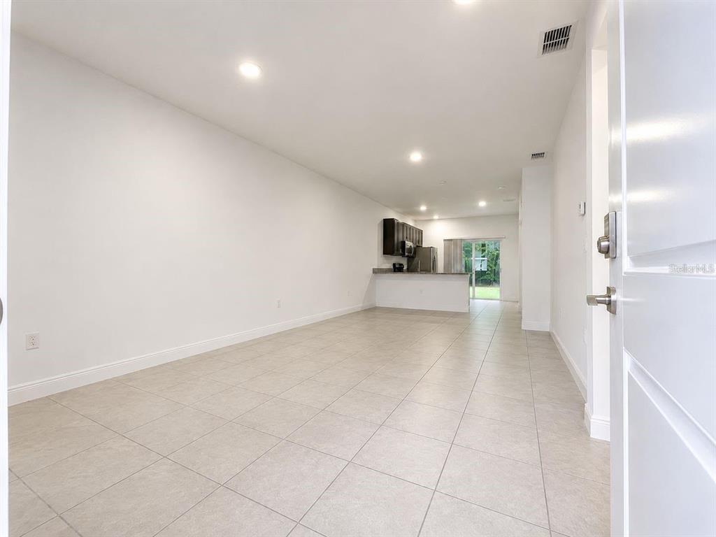 An open-concept living area features light tile flooring and a kitchen with dark cabinetry — 13664 SW 61ST CIRCLE UNIT #2, OCALA, FL