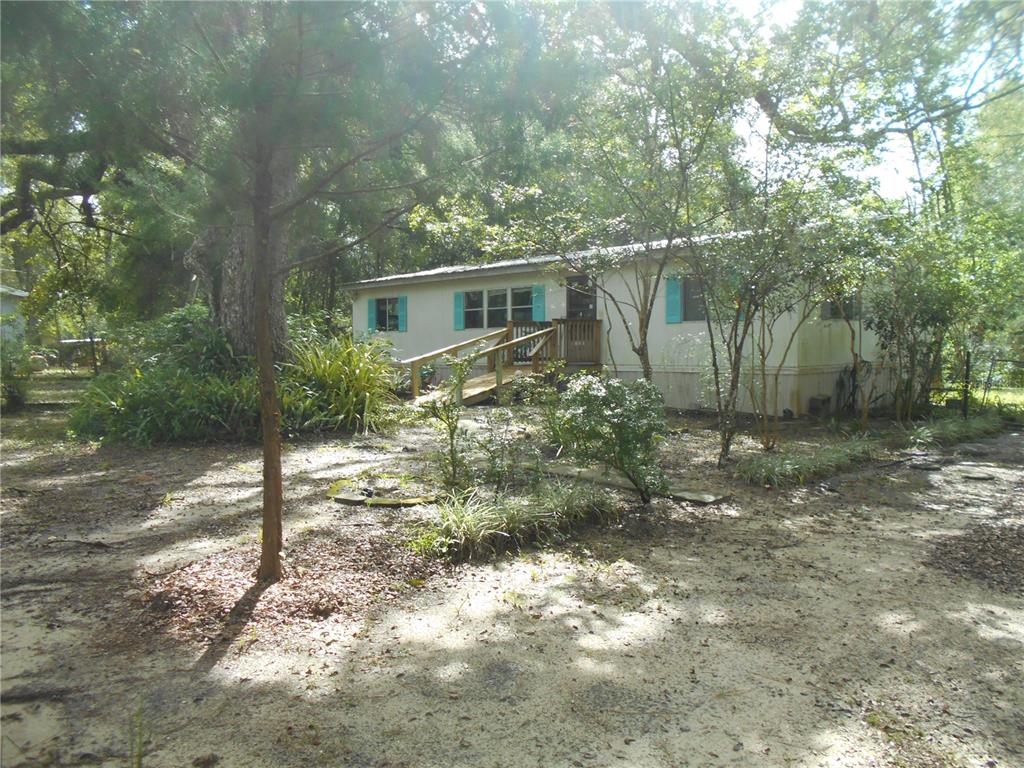 A large, moss-covered oak tree stands in the yard next to a mobile home — 20425 NE 143RD STREET, SALT SPRINGS, FL