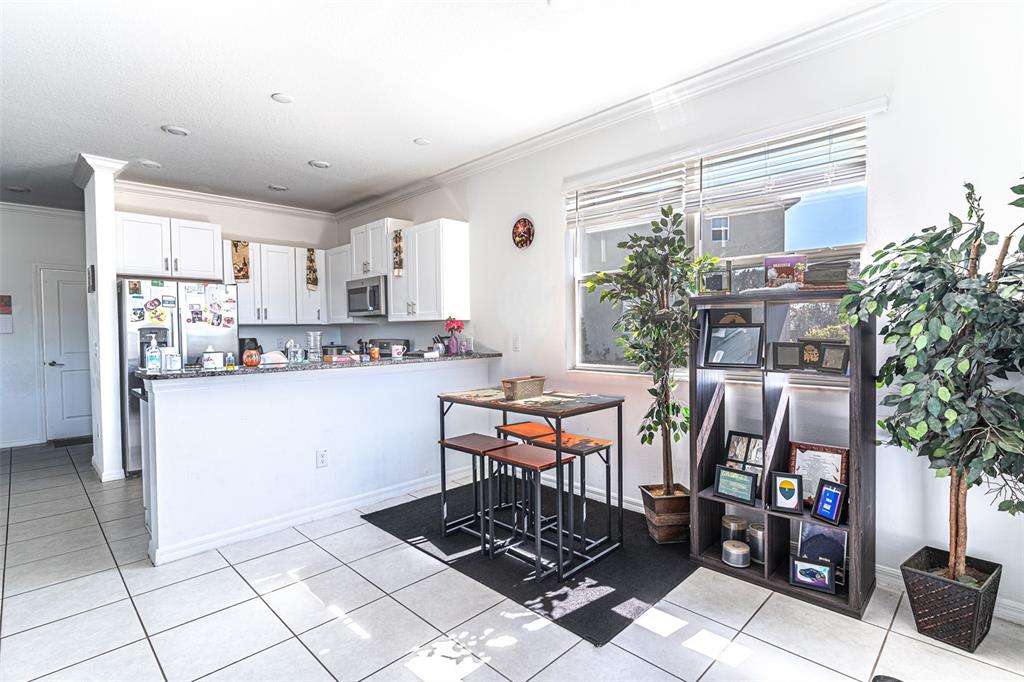 A kitchen with white cabinets and a breakfast bar next to a dining area — 7014 RIPPLE POND LOOP, ZEPHYRHILLS, FL