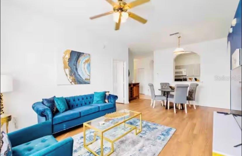 A living room features a blue tufted sofa, a glass coffee table, and dining area — 8103 COCONUT PALM WAY UNIT 302, KISSIMMEE, FL