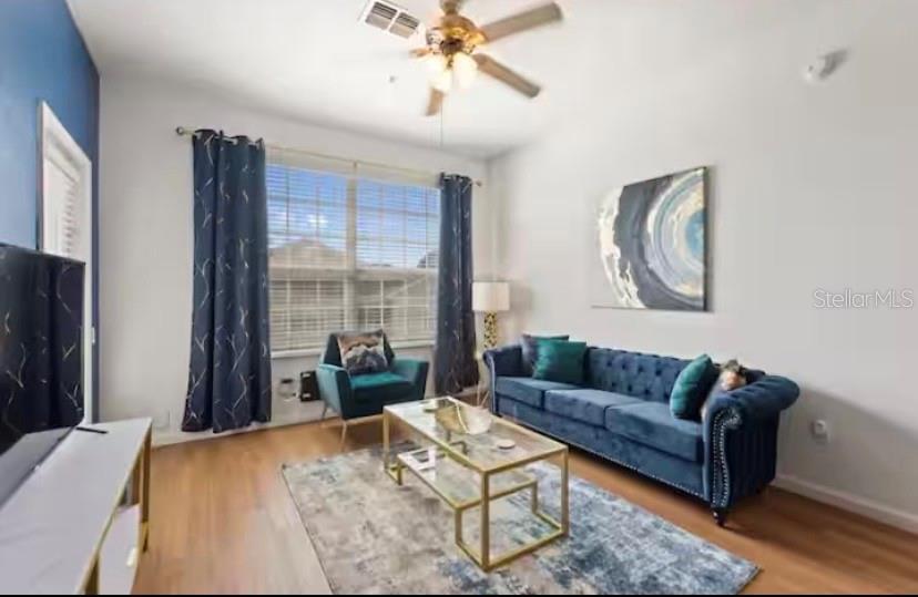 A living room features a blue tufted sofa, a glass coffee table, and a ceiling fan — 8103 COCONUT PALM WAY UNIT 302, KISSIMMEE, FL