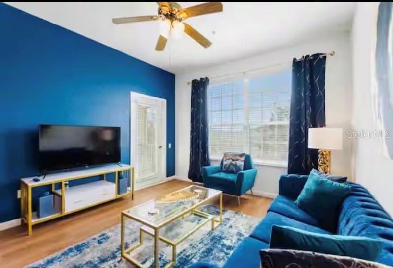 A living room features a blue accent wall, a blue sofa, and a glass coffee table — 8103 COCONUT PALM WAY UNIT 302, KISSIMMEE, FL