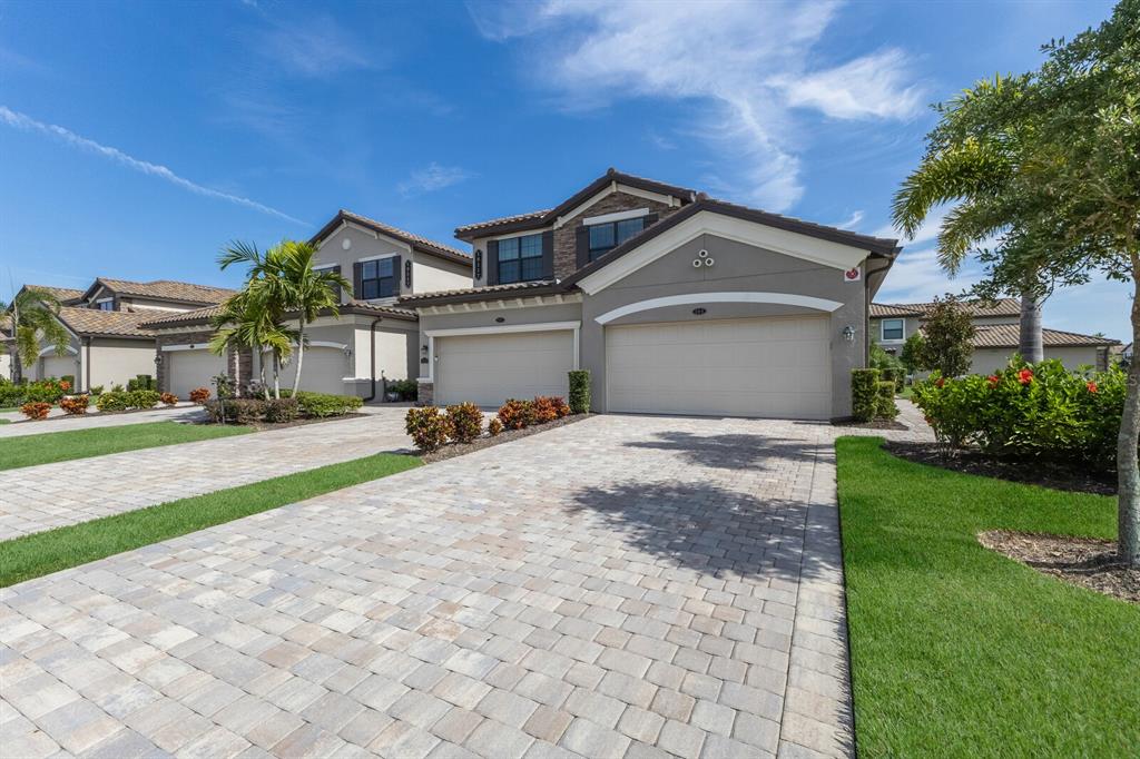 A two-story house with a beige stucco exterior, a three-car garage, and a paved driveway — 18117 GAWTHROP DRIVE UNIT 104, BRADENTON, FL