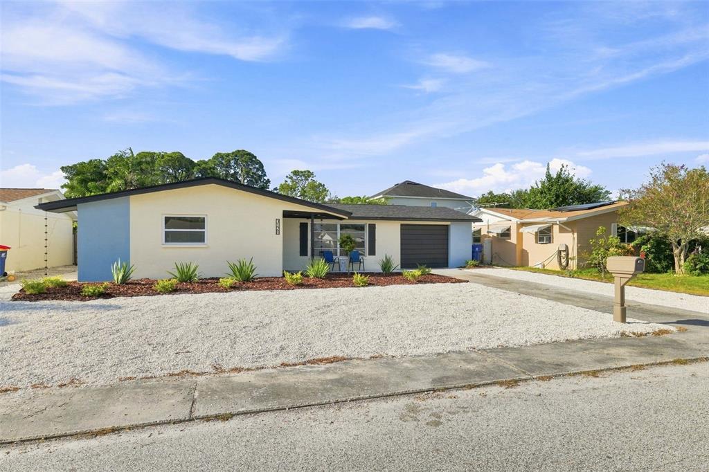A single-story house with a light-colored exterior, blue accent wall, and a gravel front yard — 3128 HARVARDSTON LOOP, HOLIDAY, FL