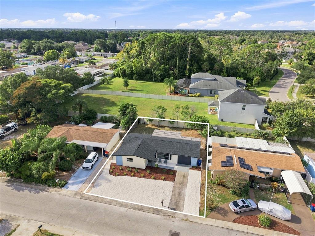 An aerial view shows a single-story house with a gravel front yard and fenced backyard — 3128 HARVARDSTON LOOP, HOLIDAY, FL