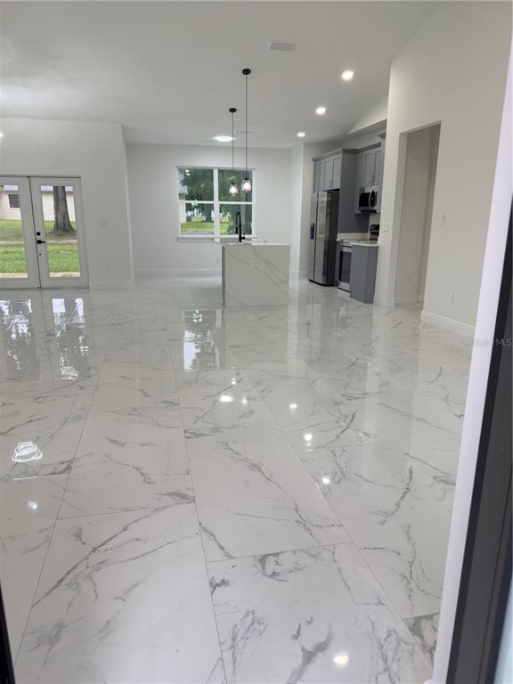 An open-concept kitchen and living area features white marble-look tile flooring and a center island — 12320 SE 70TH AVENUE, BELLEVIEW, FL