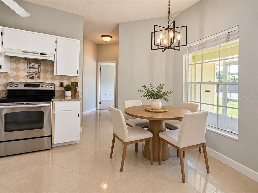 An open-concept living and dining area features light gray walls, tile flooring, and a ceiling fan — 888 FRANKLIN CIRCLE, PALM HARBOR, FL