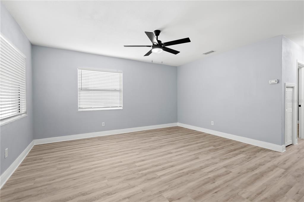 An empty room with light gray walls, light wood-look flooring, and a ceiling fan — 3921 W GRAY STREET, TAMPA, FL