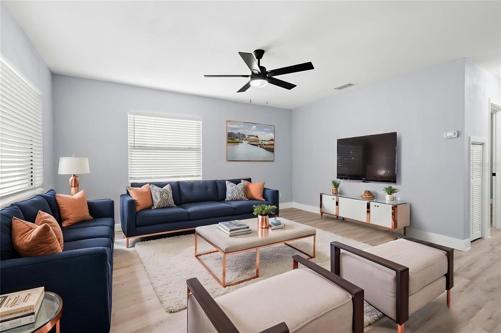 A living room features navy sofas, a coffee table, two chairs, and a wall-mounted television — 3921 W GRAY STREET, TAMPA, FL