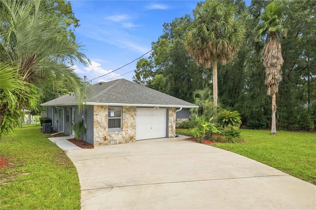 A single-story house with a stone facade, a white garage door, and a concrete driveway — 6500 CHERRY ROAD, OCALA, FL