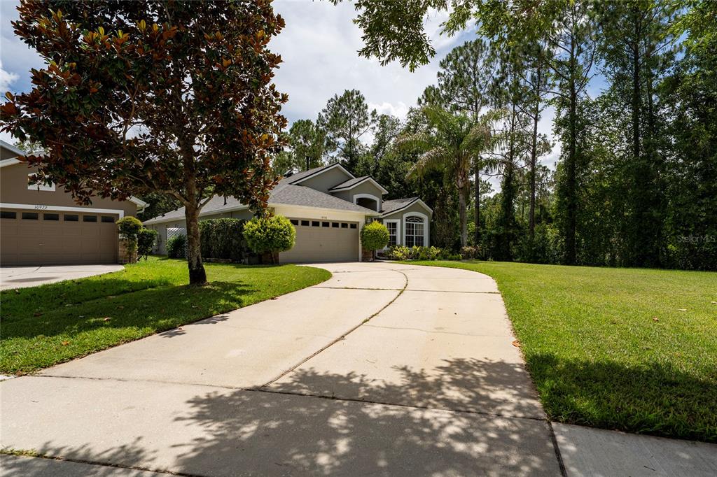 A single-story suburban house with a two-car garage, a palm tree, and a grassy lawn — 10966 ELIOTTI STREET, ORLANDO, FL
