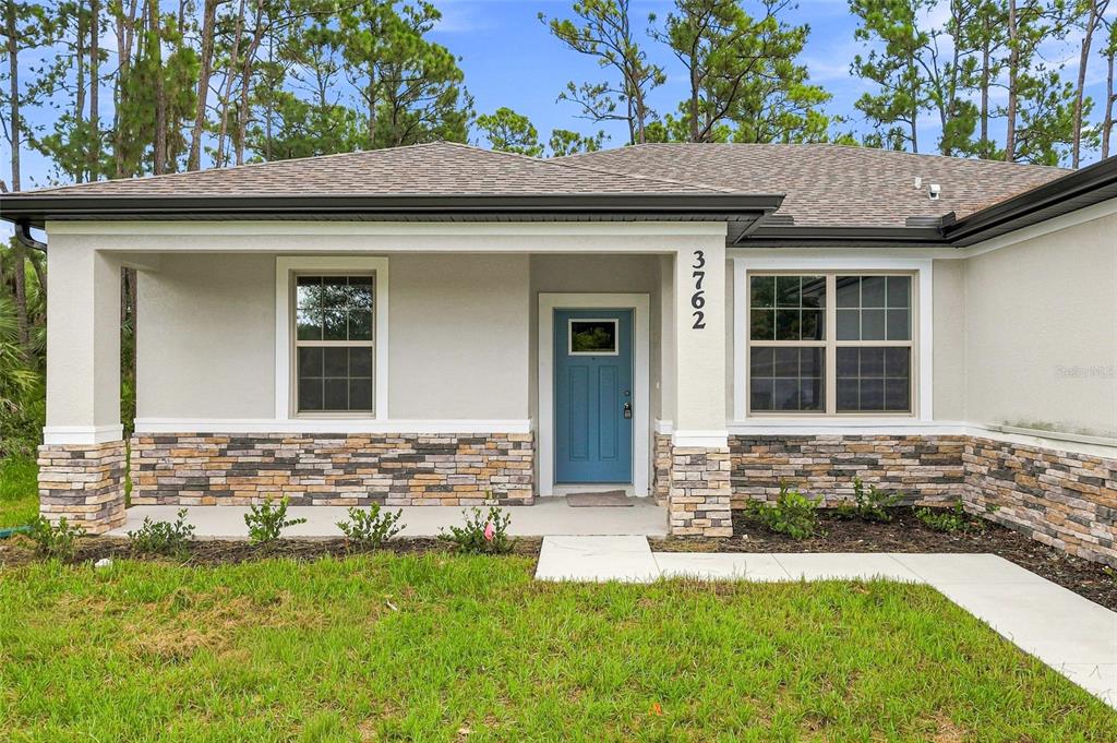 A single-story house exterior features a blue front door, stone veneer, and a covered porch — 3762 SARDINIA AVENUE, NORTH PORT, FL