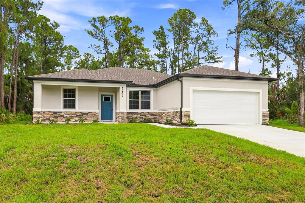 A single-story house with a blue front door, stone veneer, and a two-car garage — 3762 SARDINIA AVENUE, NORTH PORT, FL