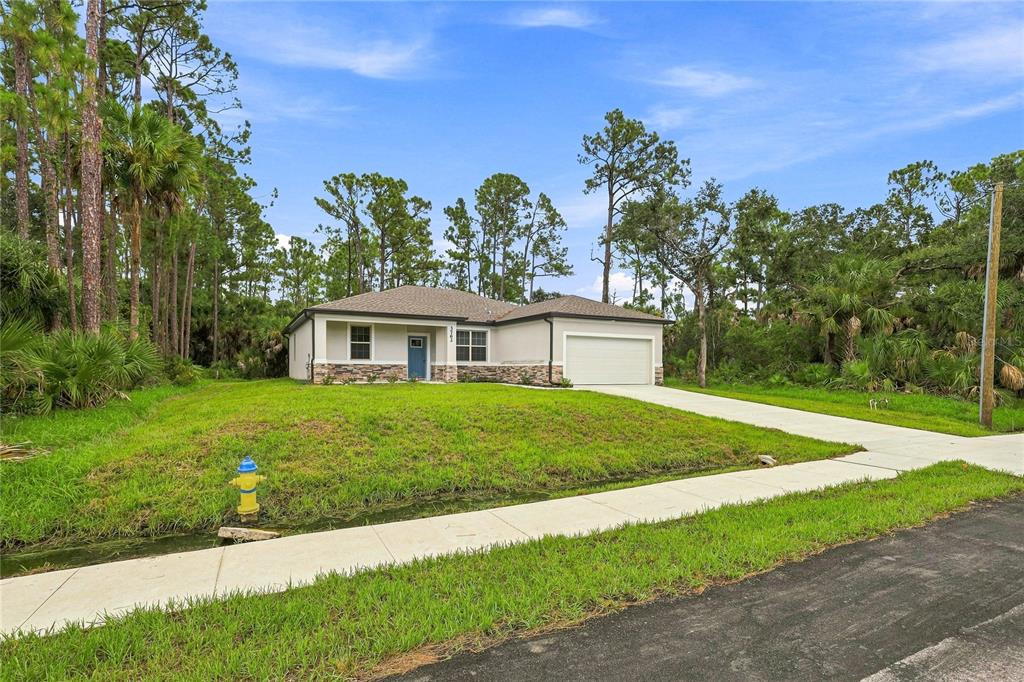 A single-story house with a stone-accented facade, a two-car garage, and a front lawn — 3762 SARDINIA AVENUE, NORTH PORT, FL