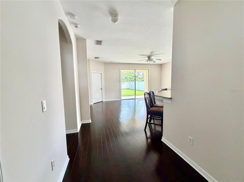 A view from a hallway into a living area with dark wood floors and sliding doors — 4004 LANGDRUM DRIVE, WESLEY CHAPEL, FL