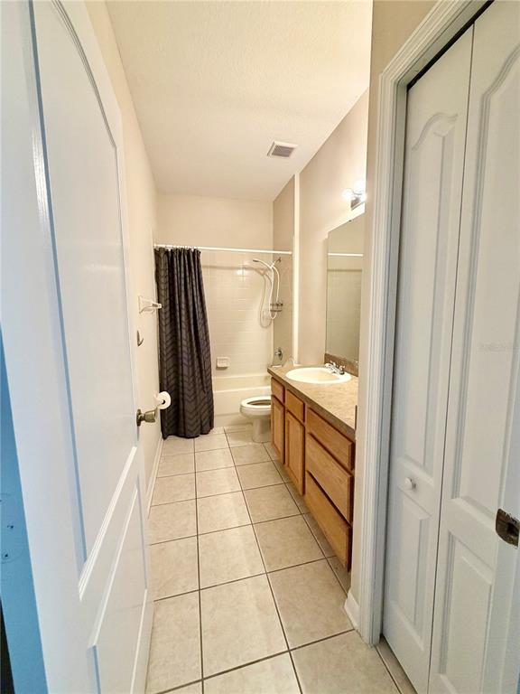 A bathroom features a tiled floor, a wooden vanity, a toilet, and a shower-tub combination — 4004 LANGDRUM DRIVE, WESLEY CHAPEL, FL