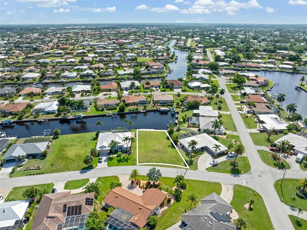 An aerial view shows a vacant residential lot outlined in white between two houses — 834 SANTA MARGERITA LANE, PUNTA GORDA, FL