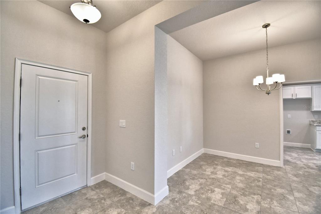 An entryway with tile flooring leads into a dining area featuring a hanging chandelier — 4641 CALAMINT LANE, AUBURNDALE, FL