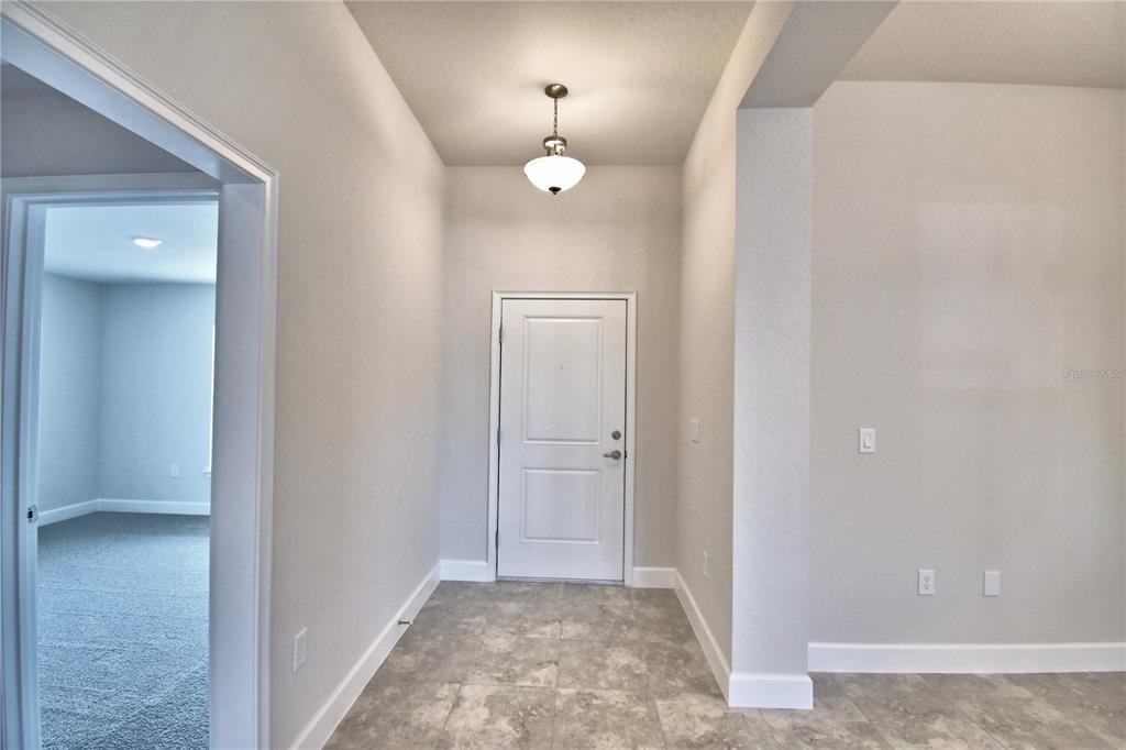 An entryway features a white front door, tile flooring, and a hanging light fixture — 4641 CALAMINT LANE, AUBURNDALE, FL