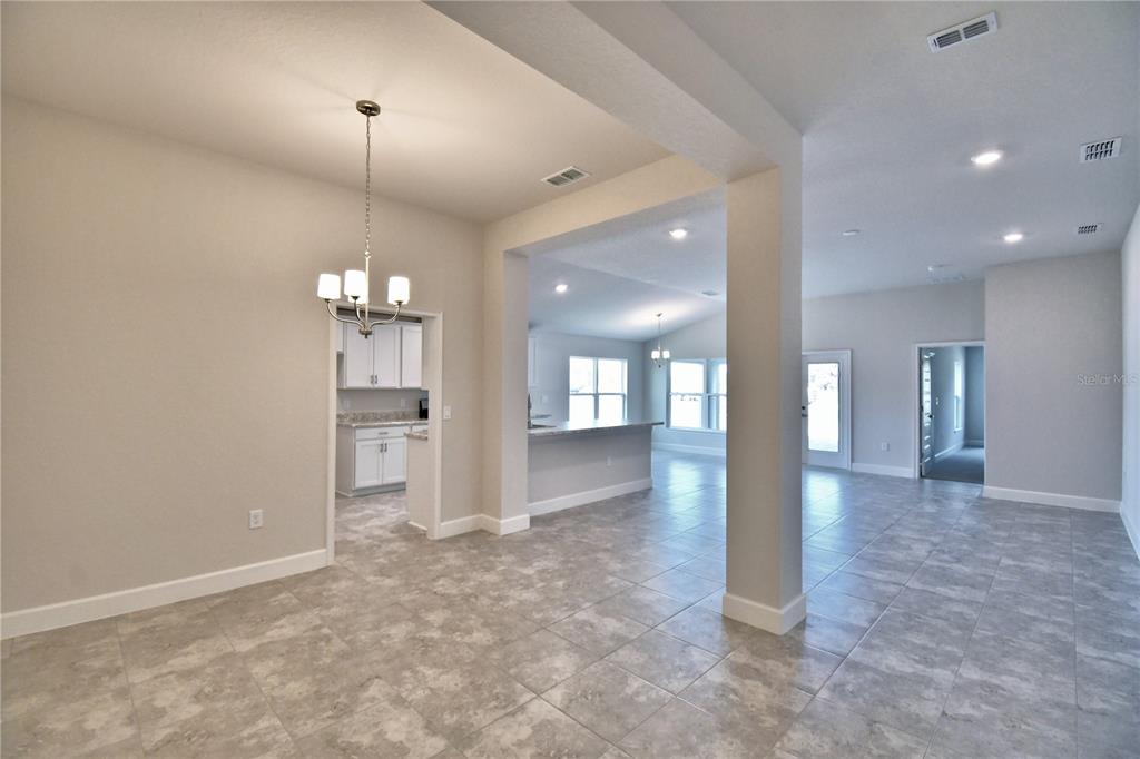 A dining area with a chandelier opens into a kitchen and a spacious living room — 4641 CALAMINT LANE, AUBURNDALE, FL