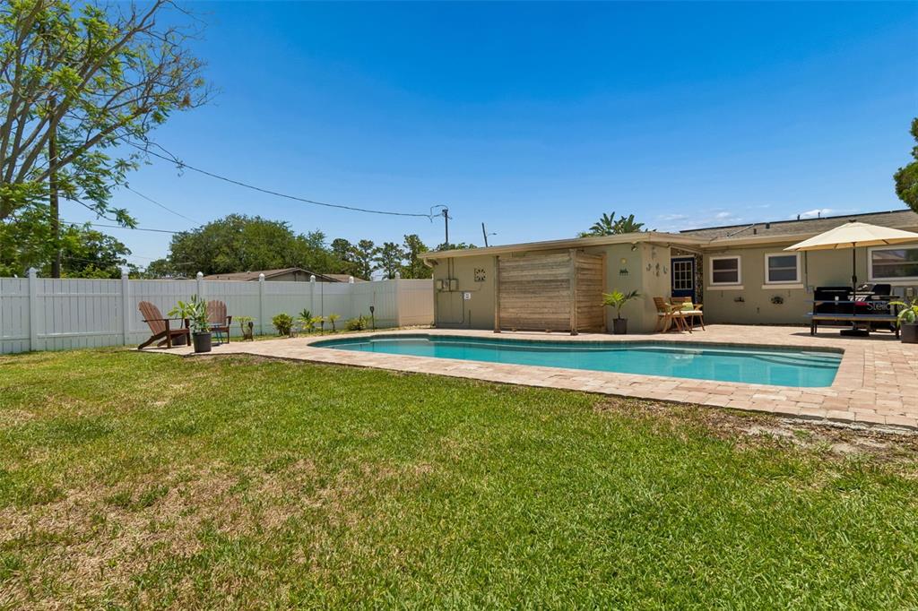 A hot tub sits on a brick patio under a covered porch with string lights — 604 7TH AVENUE SW, LARGO, FL