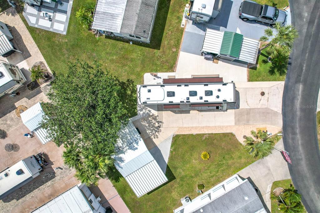 An aerial view shows a recreational vehicle parked on a concrete pad surrounded by landscaping — 190 BIG PINE AVENUE S, FROSTPROOF, FL