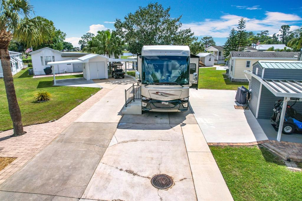 An aerial view shows a large recreational vehicle parked on a concrete driveway between two structures — 190 BIG PINE AVENUE S, FROSTPROOF, FL