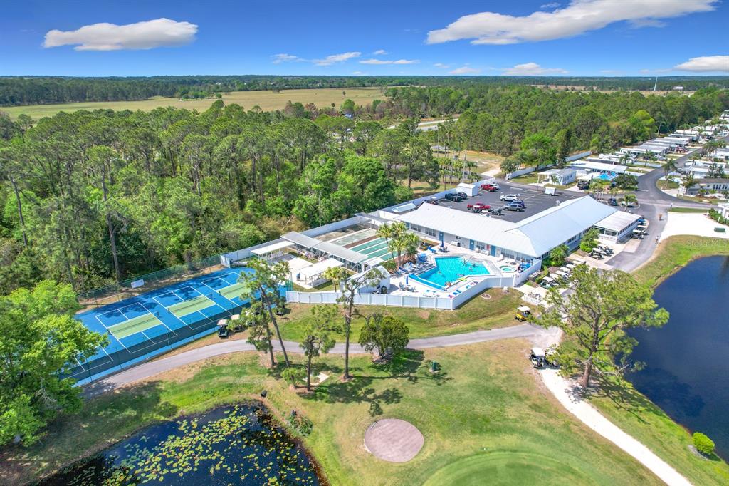 An aerial view of a community clubhouse featuring a swimming pool, tennis courts, and pond — 190 BIG PINE AVENUE S, FROSTPROOF, FL