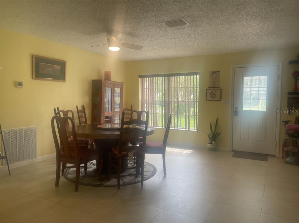 A dining area features a round wooden table, chairs, tile flooring, and a ceiling fan — 331 SHORE DRIVE E, OLDSMAR, FL