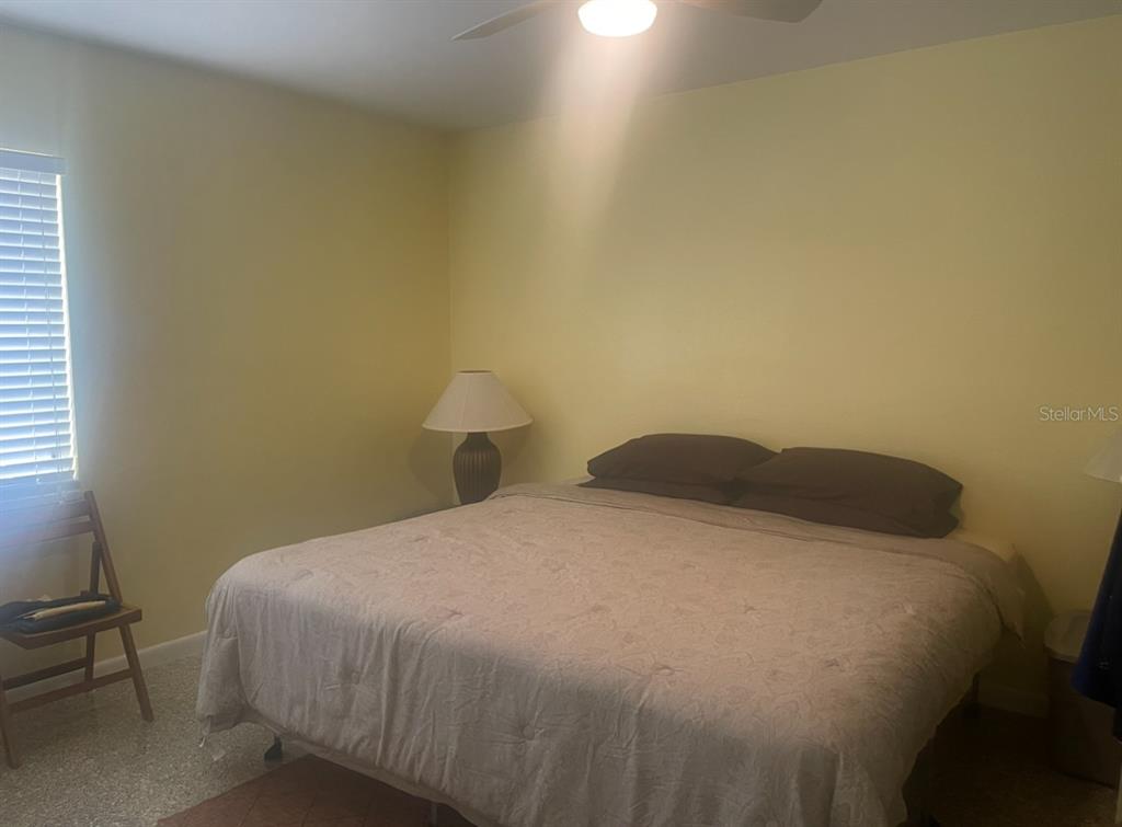 A bedroom features a bed with a tan comforter, a lamp, and a wooden chair — 331 SHORE DRIVE E, OLDSMAR, FL