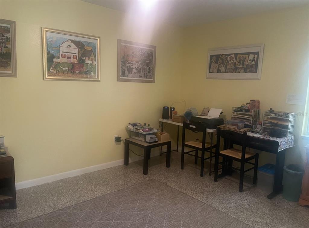 A room with yellow walls, framed artwork, and a desk area with chairs — 331 SHORE DRIVE E, OLDSMAR, FL