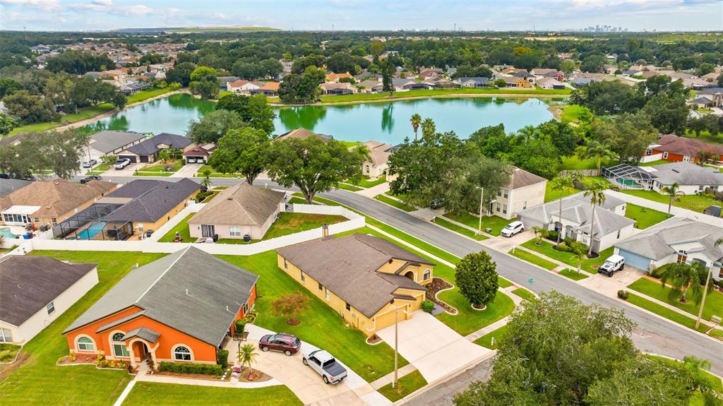 An aerial view shows suburban houses with swimming pools near a lake in a neighborhood — 1803 CATTLEMAN DRIVE, BRANDON, FL