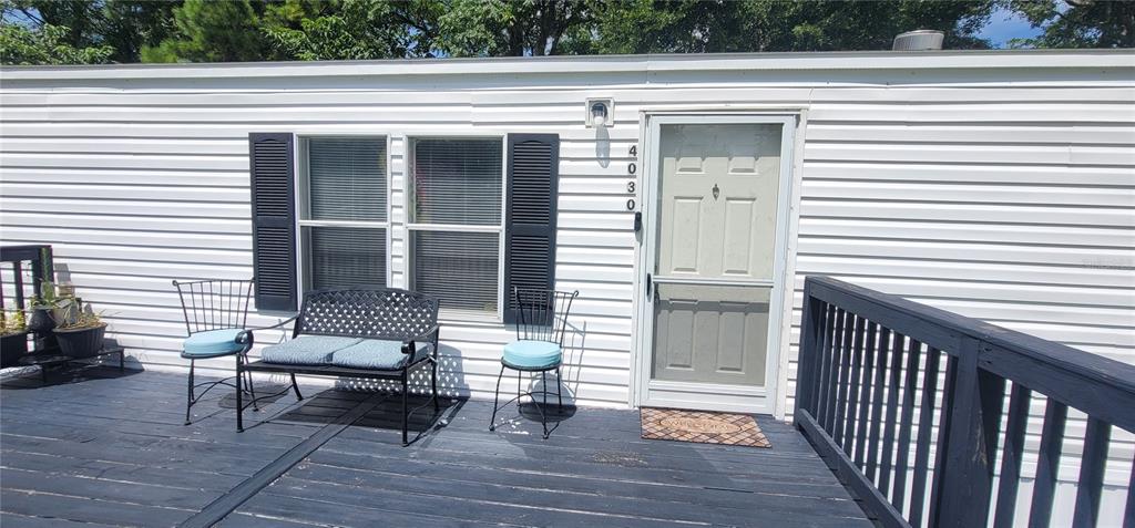 A white mobile home with a black deck and a satellite dish sits behind a fence — 4030 NE 212TH TERRACE, WILLISTON, FL