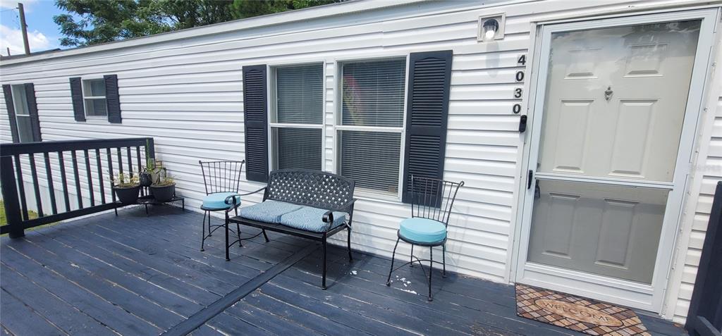 A white mobile home with a wooden deck sits on a grassy lot with trees — 4030 NE 212TH TERRACE, WILLISTON, FL