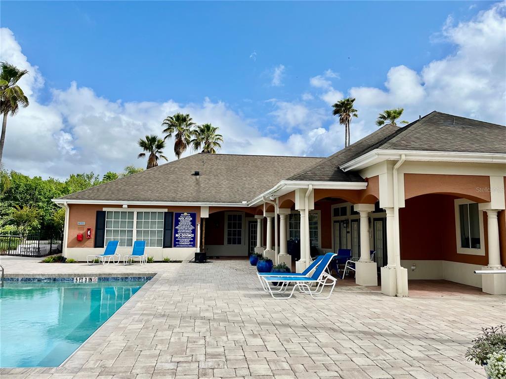 A swimming pool with a paved deck sits beside a house with a covered patio — 1939 SUMMER CLUB APT DRIVE UNIT 315, OVIEDO, FL