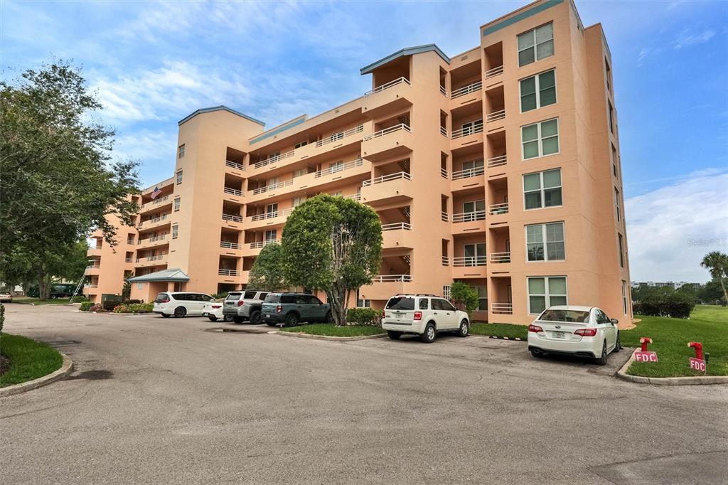 A multi-story peach-colored apartment building with balconies and a parking lot in front — 4570 PINEBROOK CIRCLE CIRCLE UNIT 404, BRADENTON, FL
