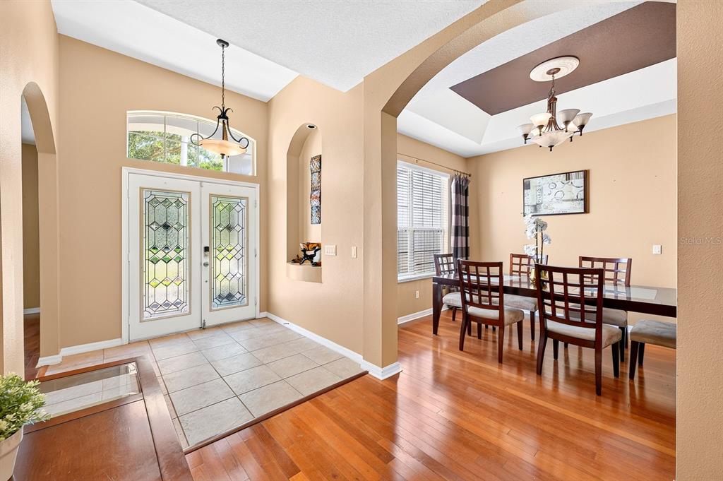 A dining room features a wooden table, six chairs, hardwood floors, and a tray ceiling — 13537 KITTY FORK ROAD, ORLANDO, FL