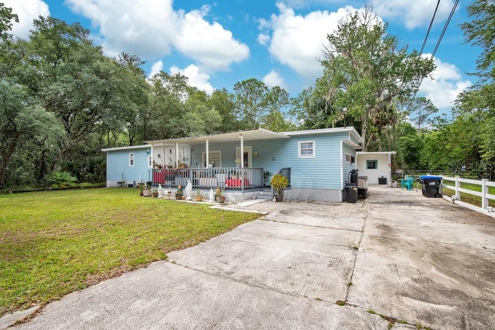 A light blue mobile home with a front porch and a concrete driveway — 18222 LYNBROOK ROAD, ORLANDO, FL