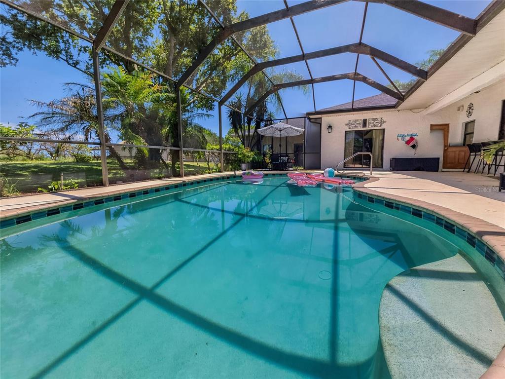 A two-story house with beige siding, a wrap-around porch, and palm trees on a lawn — 915 N CROOKED LAKE DRIVE, BABSON PARK, FL